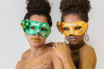 Two beautiful young women with their bodies painted in gold. Young African-American women dressed up as masks and with their bodies painted for the carnival.