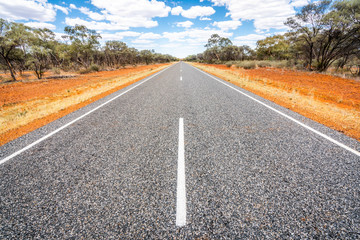 Straight road with white lines in middle of outback red centre Australia