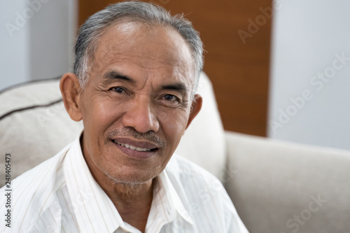 Fotografía asian senior oldman sitting on the sofa smile when look at the camera
