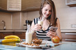 © Artem - Woman drinking organic almond milk holding a phone in her hand in the kitchen. Diet healthy vegetarian product