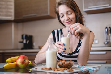 Woman drinking organic almond milk holding a glass in her hand in the kitchen. Diet healthy vegetarian product