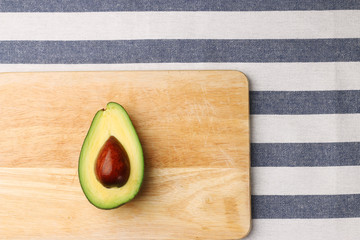 Wall Mural - half avocado on wooden and textile background top view