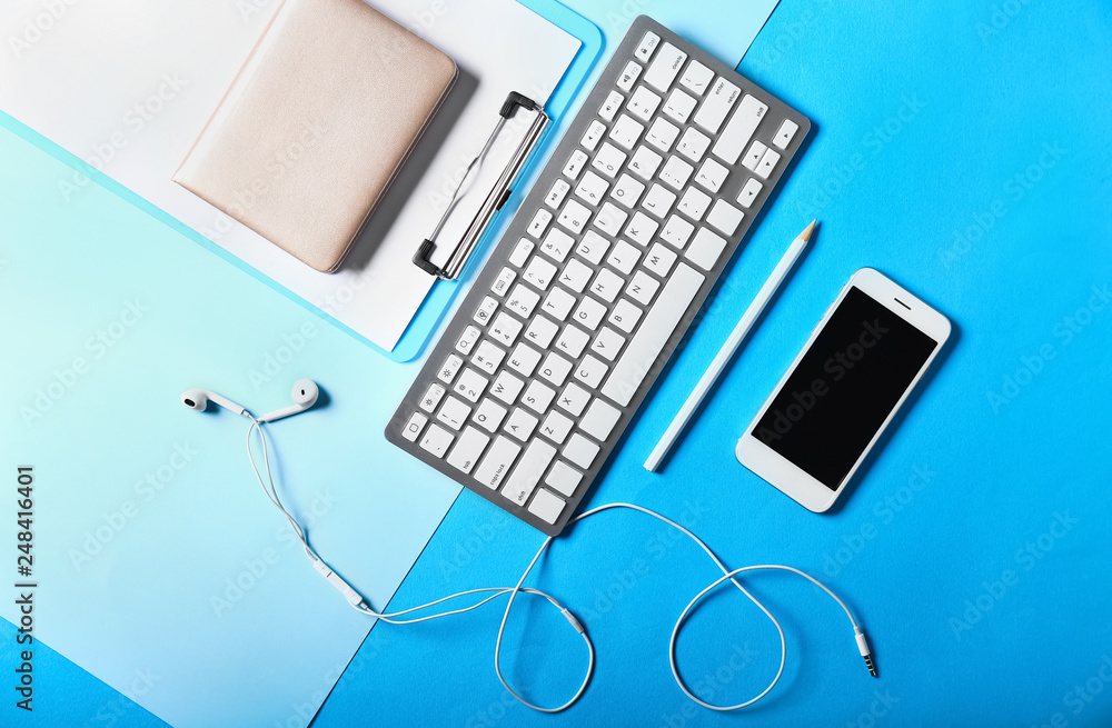 Stylish workplace with stationery, mobile phone and computer keyboard on color background