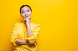 Happy woman thinking and standing isolated over yellow background
