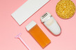 Beauty, depilation and hair removal concept - wax, spatula, epilator and safety razor on pink background. Top view.
