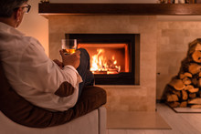 Man Sitting At Home By The Fireplace And Drinking A Whiskey.  