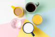 Coffee tea and other drinks in colorful cups on a multicolored background, top view