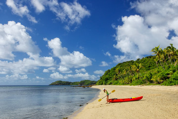 Wall Mural - Young woman with red sea kayak on a sandy beach