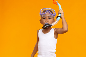 Horizontal image of skinny black African American boy of school age wearing mask and snorkel while diving in ocean during summer vacations. Holiday, summertime, childhood, rest and relaxation