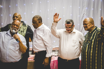 Group of mixed race men praying and worshiping together