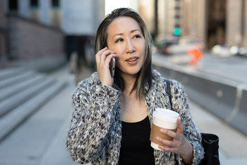 Wall Mural - Asian woman in city walking street talking on cell phone