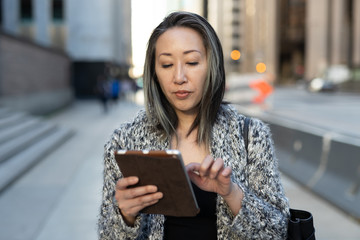 Wall Mural - Asian woman in city walking using tablet computer