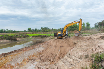 Wall Mural - Yellow excavator machine working earth moving works at construction site