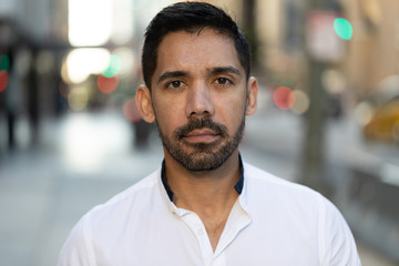 Young Latino Hispanic man in city serious angry face