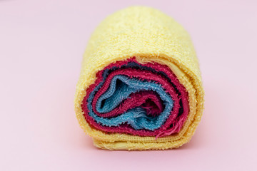 colored towels rolled up, pink background