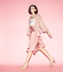 young fashion woman in pink clothes run on pink background, full lenght