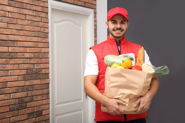 Canvas Print - Food delivery courier holding paper bag with products indoors. Space for text