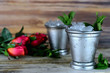 Image for Kentucky Derby in May showing two silver mint julep cups with crushed ice and fresh mint in a rustic setting with red roses
