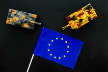 War, Military Threat, Military Power Concept. European Union. Tanks Toy Near European Flag On Black Background Top View