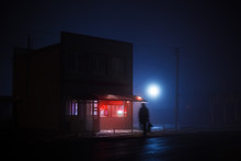 Night Blue Misty Landscape. A Small Shop With A Red Illuminated Signboard Stands On The Side Of The Road, A Greasy Silhouette Of A Man Crosses The Road