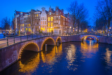 Canals Of Amsterdam With Dutch Buildings At Night In Amsterdam City, Netherlands