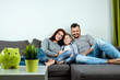 © Aliaksandr Marko - Happy parents and son having fun, tickling sitting together on the sofa, cheerful couple laughing, playing a game with their son, family fun.