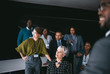 © JonoErasmus - Business group having a discussion, looking and pointing to a large video wall with charts and graphs out of frame