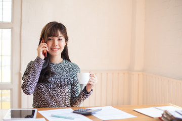 Portrait of Beautiful businesswoman sitting at desk and talk on smart phone 