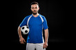 © LIGHTFIELD STUDIOS - bearded football player standing with ball isolated on black