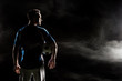 © LIGHTFIELD STUDIOS - silhouette of football player holding ball on black with smoke