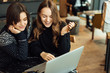 © Serhiy Hipskyy - Two girls, friends Drink Hot Coffee While Work In Cafe On Laptop. Portrait Of Stylish Smiling Girls In Winter Clothes Drinking Hot Coffee And Work At Laptop. Female Winter Style. - Image