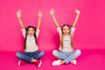 Canvas Print - Close up photo two little age she her girls hands arms up best friends sit floor legs crossed winners wearing casual jeans denim checkered plaid shirts isolated rose vibrant vivid background