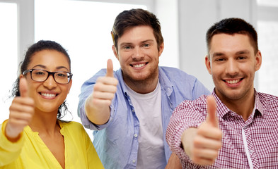 Canvas Print - business and people concept - happy international creative team at office showing thumbs up