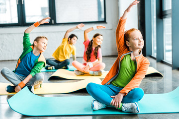 Wall Mural - Happy kids stretching on fitness mats with smile