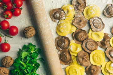 Wall Mural - Homemade fresh Italian ravioli pasta on white wood table  with flour, basil, tomatoes,background,top view.