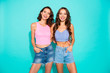 Close up portrait two stunning beautiful confident she her lady chic hugging revealing white teeth toothy wearing pink jeans denim shorts tank tops isolated blue teal bright vivid background