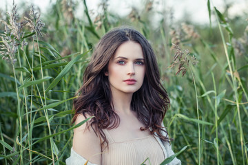 beautiful woman outdoors on green grass background in spring romantic cloudy day