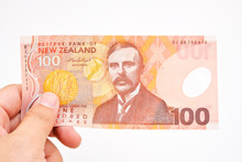 Hand Holding 100 New Zealand Doller On White Background. 