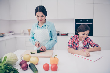 Sticker - Portrait of two nice cute lovely attractive cheerful cheery dreamy people mom making lunch healthy lifestyle girl doing hometask in light white kitchen interior indoors