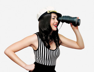 Beautiful smiling young brunette woman sailor looking away through binoculars on white background