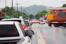 Blurred Images Of Trains Moving Through Bulkheads With Vehicles Waiting To Stop While It Rains.