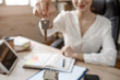 © estradaanton - Young businesswoman sit at table in room. She hold key and smile. Busy woman work. Notebook and tablet on table.