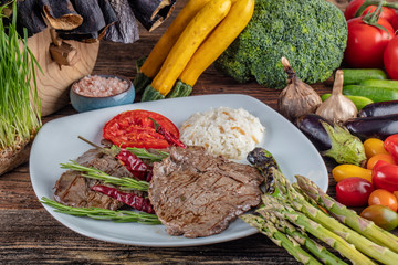 Medium rare beef tenderloin grilled, created background with vegetables on wooden background.