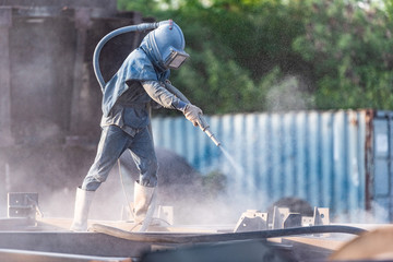 Wall Mural - Sand blasting process, Industial worker using sand blasting process preparation cleaning surface on steel before painting in factory workshop.