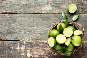 Ripe limes in basket on grey wooden table