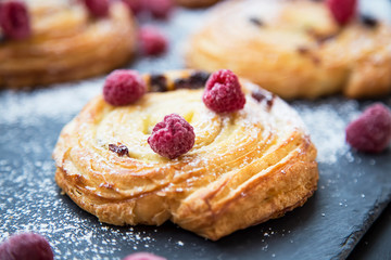 Pastry rolls with vanilla and raspberries closeup, podered sugar on top, tasty delicious pastry buns freshly baked