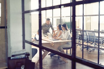 Wall Mural - Young creative people in modern office. Group of young business people are working together with laptop, tablet, smart phone, notebook. Successful hipster team in coworking. Freelancers.