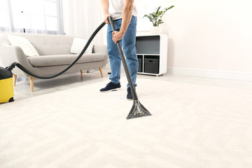 Wall Mural - Man removing dirt from carpet with vacuum cleaner indoors, closeup