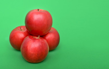 Wall Mural - Four red apples on the green background