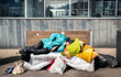 © Srdjan - Homeless man, Poor homeless man or refugee sleeping on the wooden bench on the urban street in the city with bags of clothes and junk on sunny cold day, social documentary concept